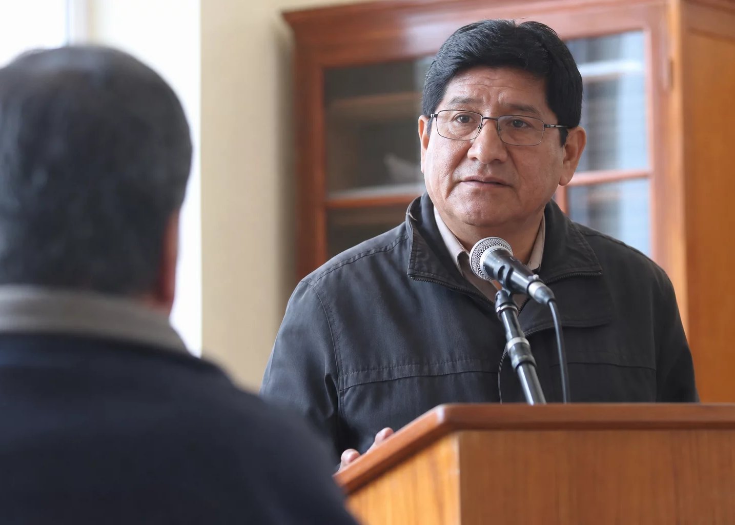 Un micrófono en el atril, con alguien de pie al fondo